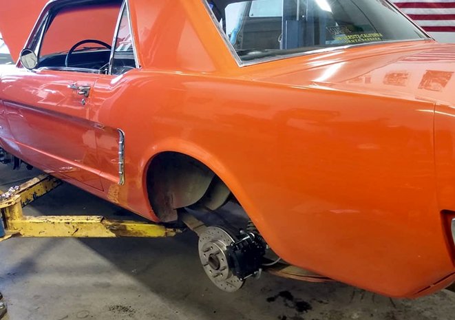 Orange 65 Ford Mustang on a rack with new disc brakes